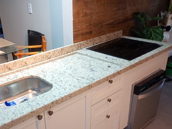 Bancada de cozinha em pedra clara com cooktop e cuba