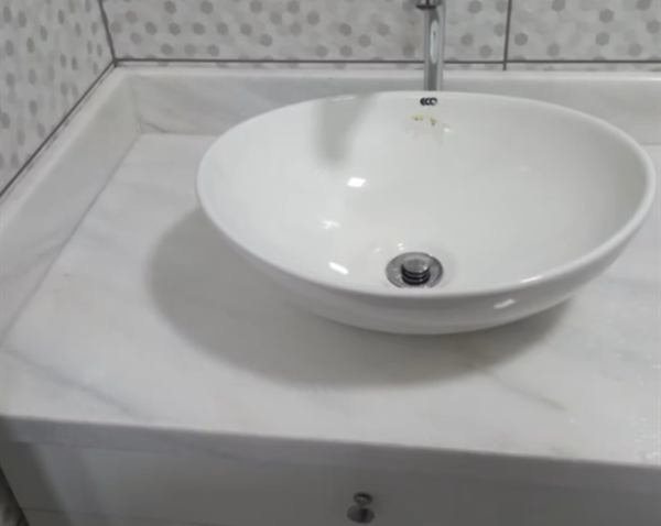 Bancada de banheiro em pedra clara com cuba de apoio