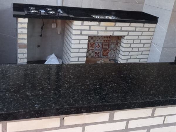 Área gourmet com bancada em pedra escura e cooktop