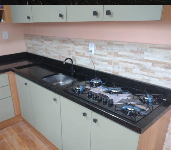 Bancada de cozinha em pedra escura com cooktop e cuba